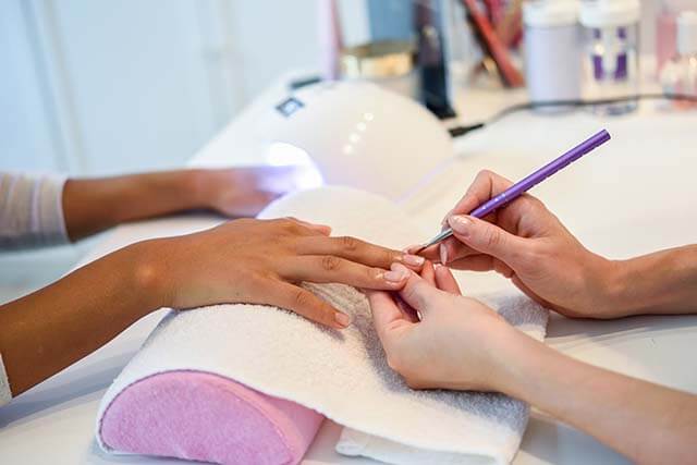 A nail salon appointment app user nail artist is applying manicure to her customer.